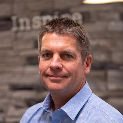 Chiropractor Scott Stoner Smiling In Front Of Blurred Stone Wall