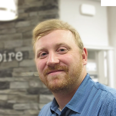 Chiropractor Seth Bearer Smiling In Front Of Blurred Stone Wall